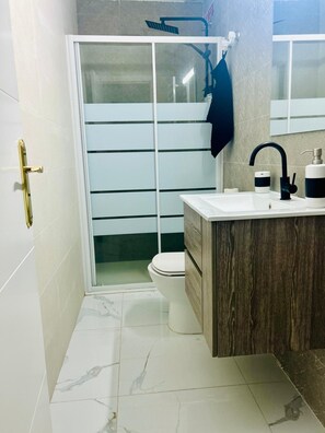 Ein modernes Badezimmer mit Toilette, Duschkabine und Waschtisch mit Spiegel.