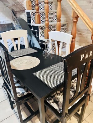 Ein Esstisch mit vier Stühlen, einer schwarzen Tischdecke und einer gewebten Tischmatte.