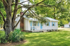 A small white house with blue shutters, a porch, and a large tree in front. - The Birdhouse, Pet-Friendly 3BR by Velvet Ditch (Oxford)