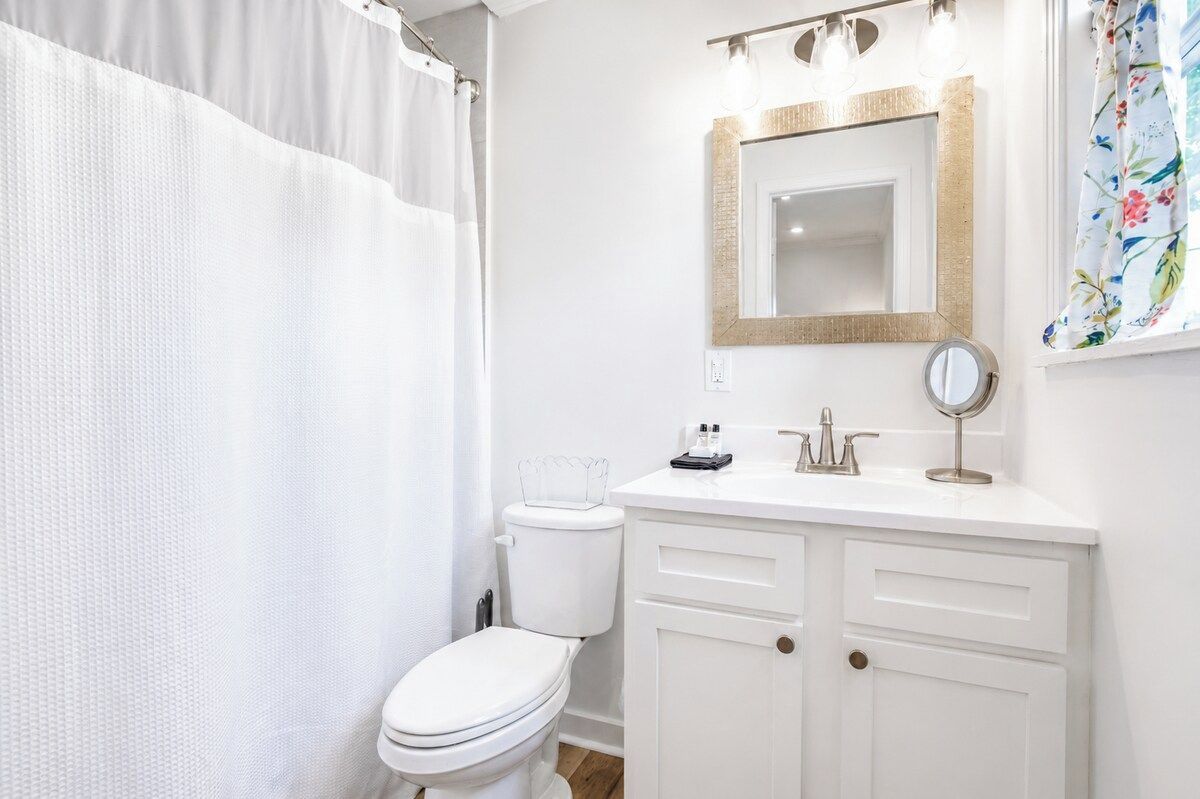 A bathroom with a white toilet, a white sink with a mirror, and a shower curtain.