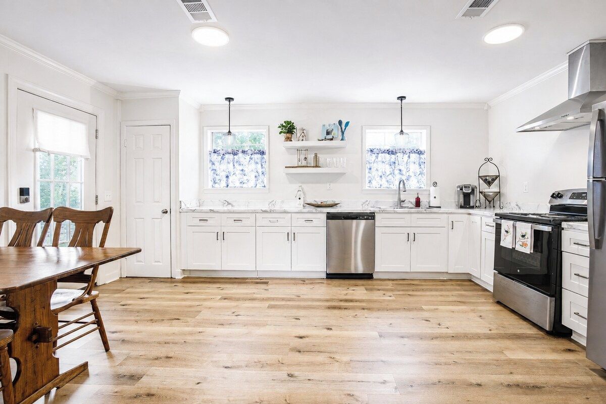 A modern kitchen with white cabinetry, a stainless steel dishwasher, and a built-in oven.