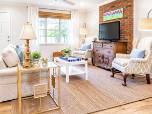 A living room with a sofa, armchairs, a coffee table, a TV, and a fireplace. - The Birdhouse, Pet-Friendly 3BR by Velvet Ditch (Oxford)