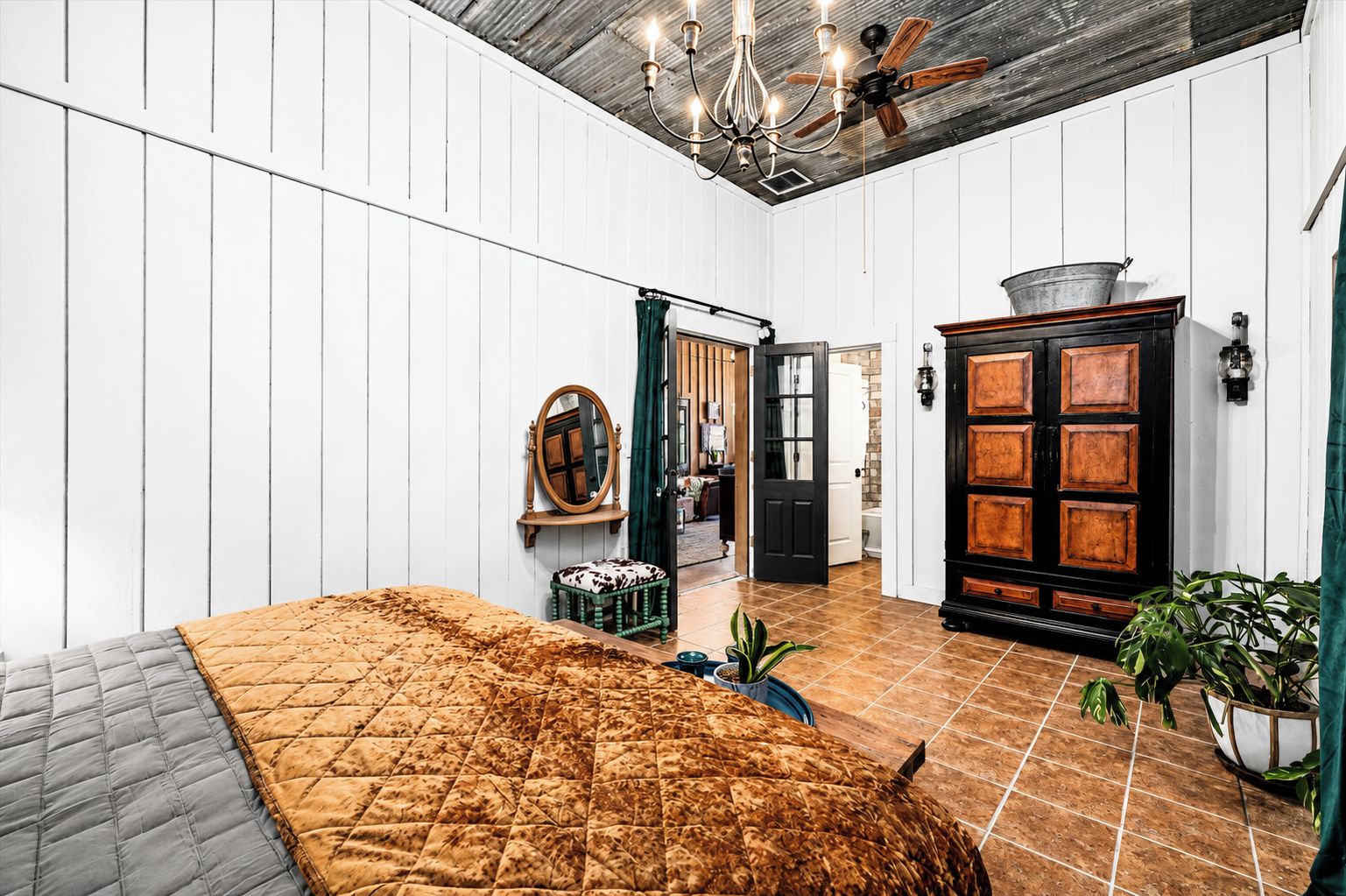A room with a bed, a wooden cabinet, a ceiling fan, and a chandelier.