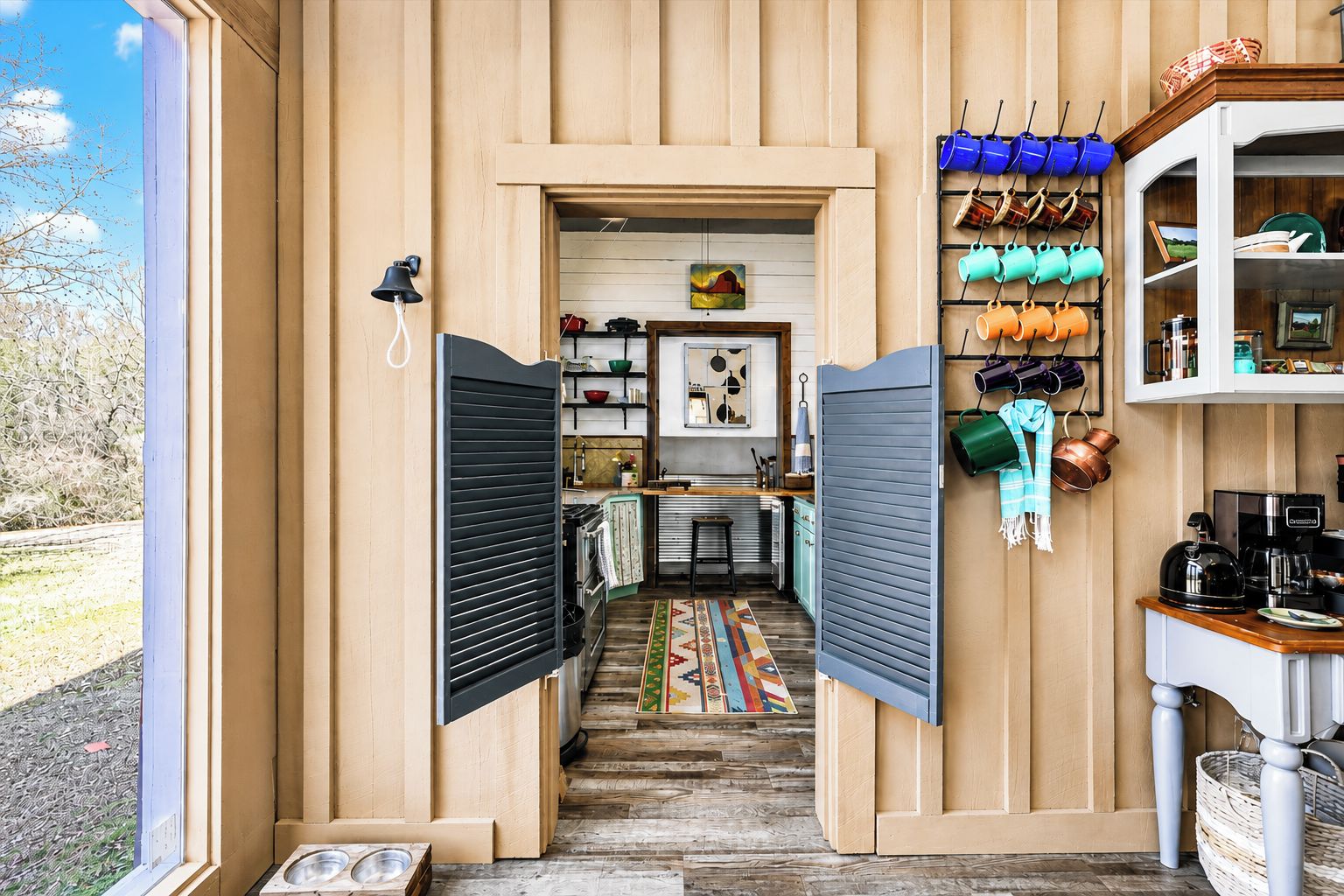 A compact kitchen with a wooden interior, a coffee machine, and a hanging pot rack.