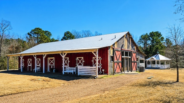 A red barn with a covered porch and a smaller structure with a gabled roof. - The Barn, Pool + Private Theater by Velvet Ditch Villas (Oxford)