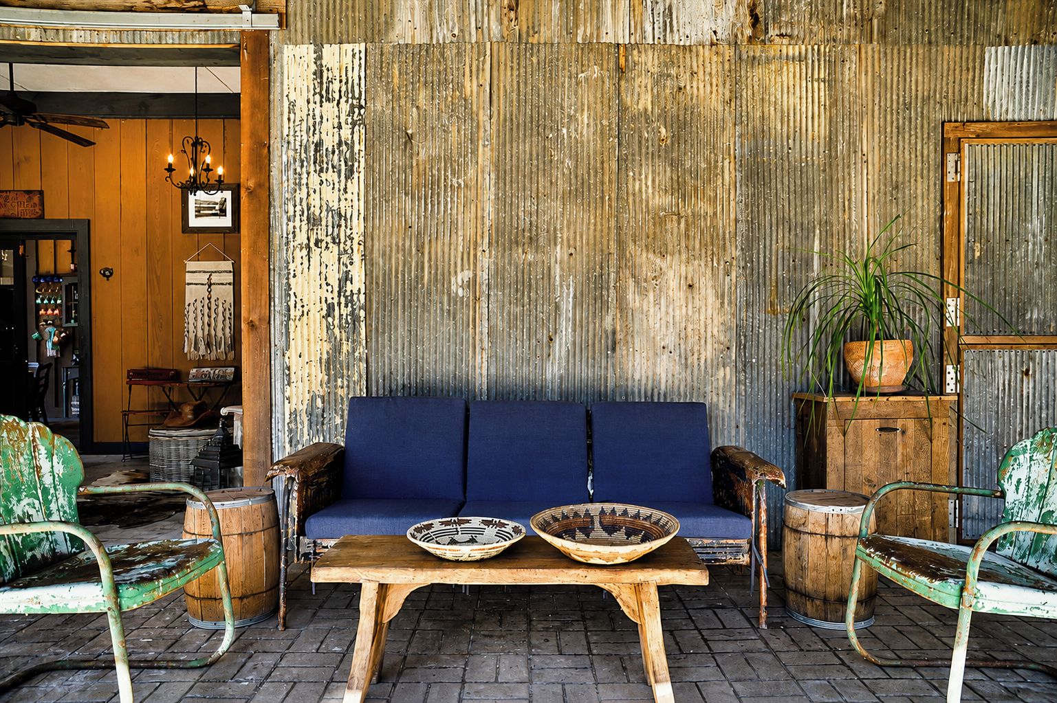 Een rustiek interieur met een blauwe bank, een houten tafel en metalen stoelen.