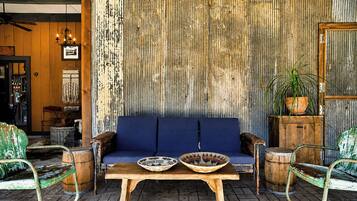 Een rustiek interieur met een blauwe bank, een houten tafel en metalen stoelen.