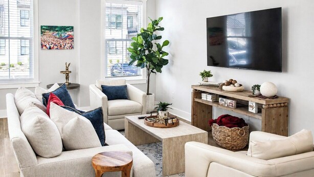 A modern living room with a sofa set, a coffee table, a TV mounted on the wall, and a large window with blinds. - The Rebel Hideout, Pool+3BR | Velvet Ditch Villas (Oxford)