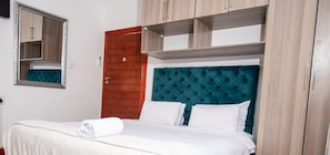 Un dormitorio con cama, espejo y armario de madera con estantes.