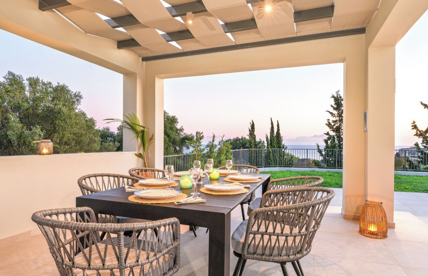 An outdoor patio with a table set for dining, wicker chairs, and a view of the landscape.