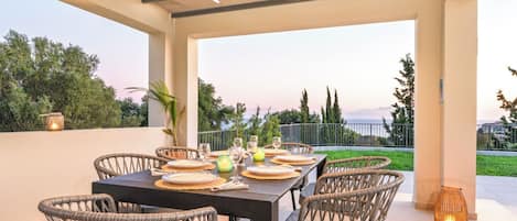 An outdoor patio with a table set for dining, wicker chairs, and a view of the landscape.