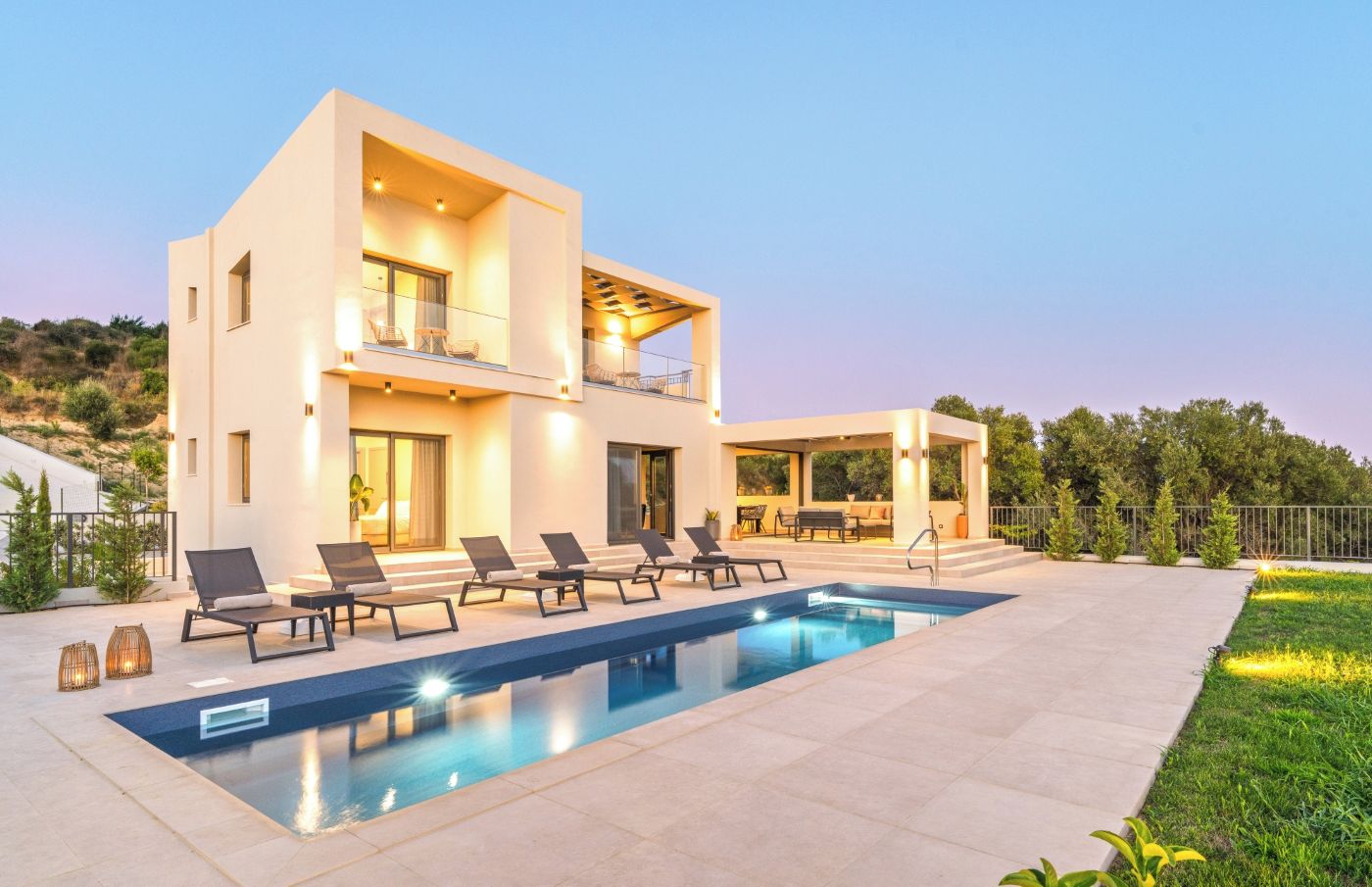 Una casa moderna de dos pisos con piscina, mobiliario exterior y un jardín cuidado.