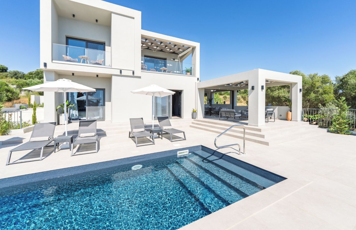 Une maison moderne à deux étages dotée d’une piscine, d’un espace salon extérieur et d’un patio couvert.