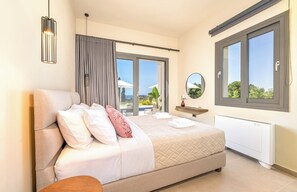 A bedroom with a bed, a bedside table, a mirror, and a window with a view. - Stylish New Villa with Sea Views Walk to Beach (Livathou)
