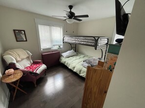 A dormitory room with a bunk bed, a desk, a chair, a window with blinds, and a ceiling fan. - Monthly 2-bedroom lake house 3 miles to St.Albans city-5 miles to I-89/hospital. (Georgia)