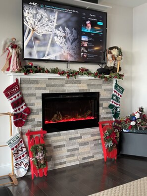Un caminetto con calze, una TV montata sopra e decorazioni natalizie.