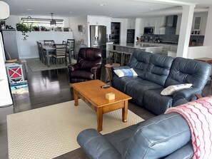 A modern living room with a leather sofa, a wooden coffee table, and a dining area in the background. - Monthly 2-bedroom lake house 3 miles to St.Albans city-5 miles to I-89/hospital. (Georgia)