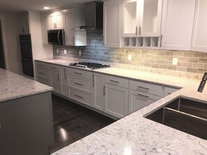 A modern kitchen with white cabinetry, a gas stove, and a microwave. - Monthly 2-bedroom lake house 3 miles to St.Albans city-5 miles to I-89/hospital. (Georgia)