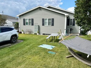 A residential house with a front yard, a hammock, a picnic table, and a parked SUV. - Monthly 2-bedroom lake house 3 miles to St.Albans city-5 miles to I-89/hospital. (Georgia)