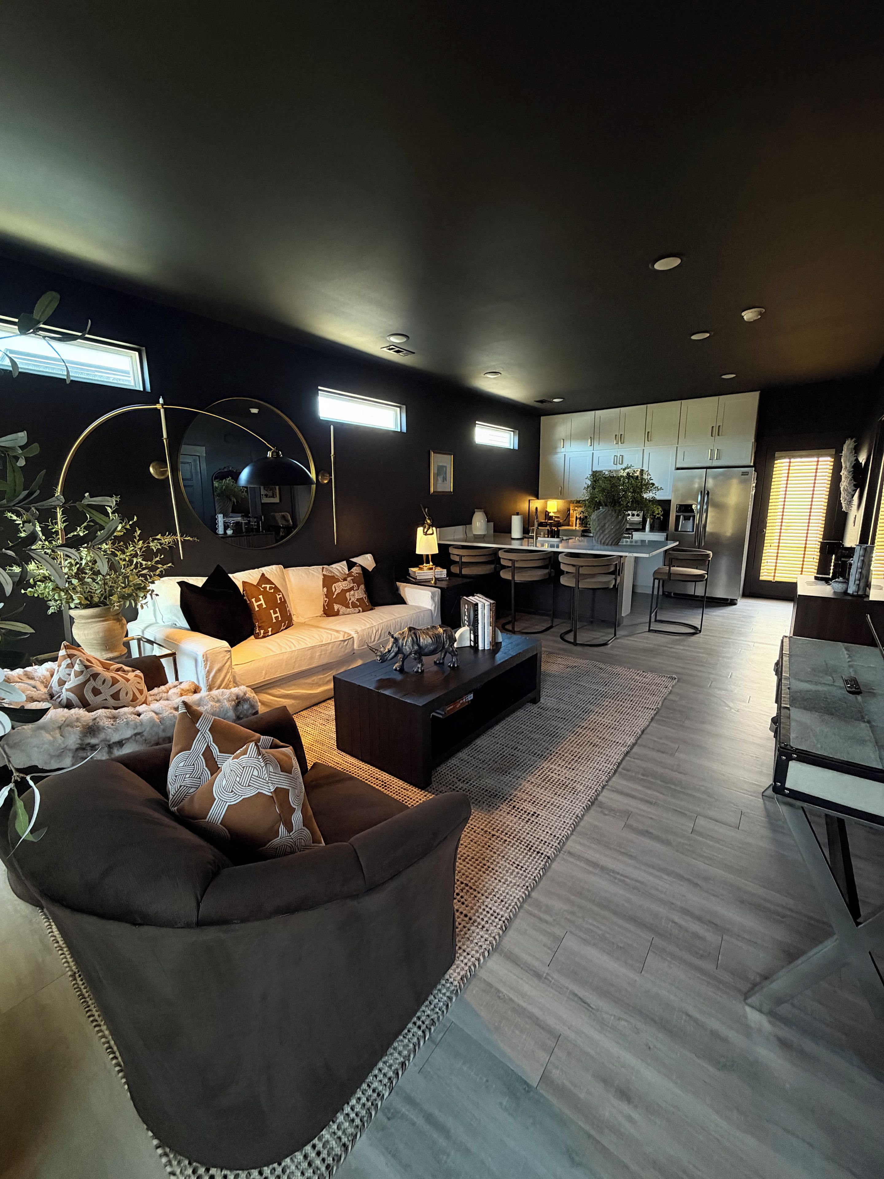 A modern living room with a sofa, coffee table, and a dining area with a kitchen in the background.