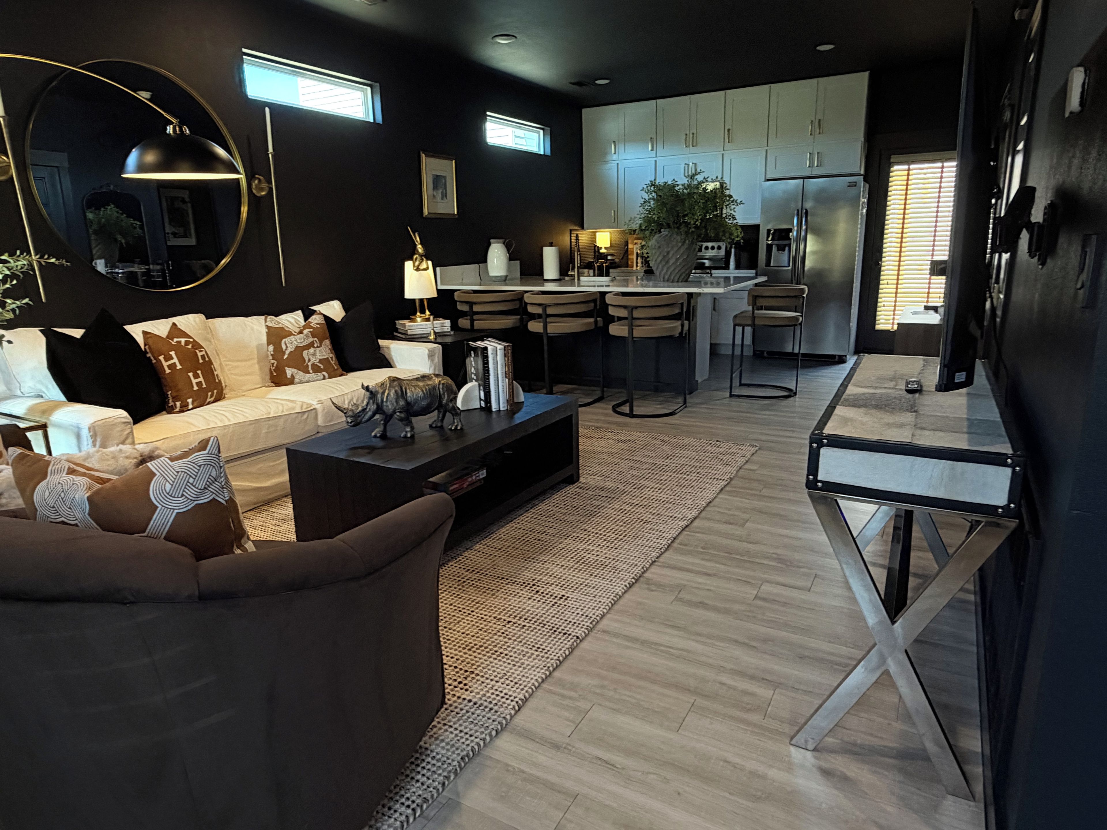 Un salon moderne avec un canapé, une table basse et un coin repas équipé de tabourets de bar.