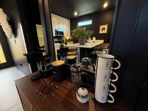 Ett modernt kök med en kaffestation, inklusive en kaffebryggare, en kaffekvarn och koppar.