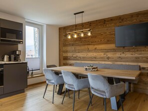 Una cocina moderna con pared de madera, una mesa de comedor con sillas y un televisor de pantalla plana montado en la pared.