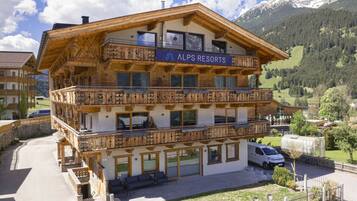 A multi-story building with balconies, labeled 'ALPS RESORTS,' surrounded by a mountainous landscape.