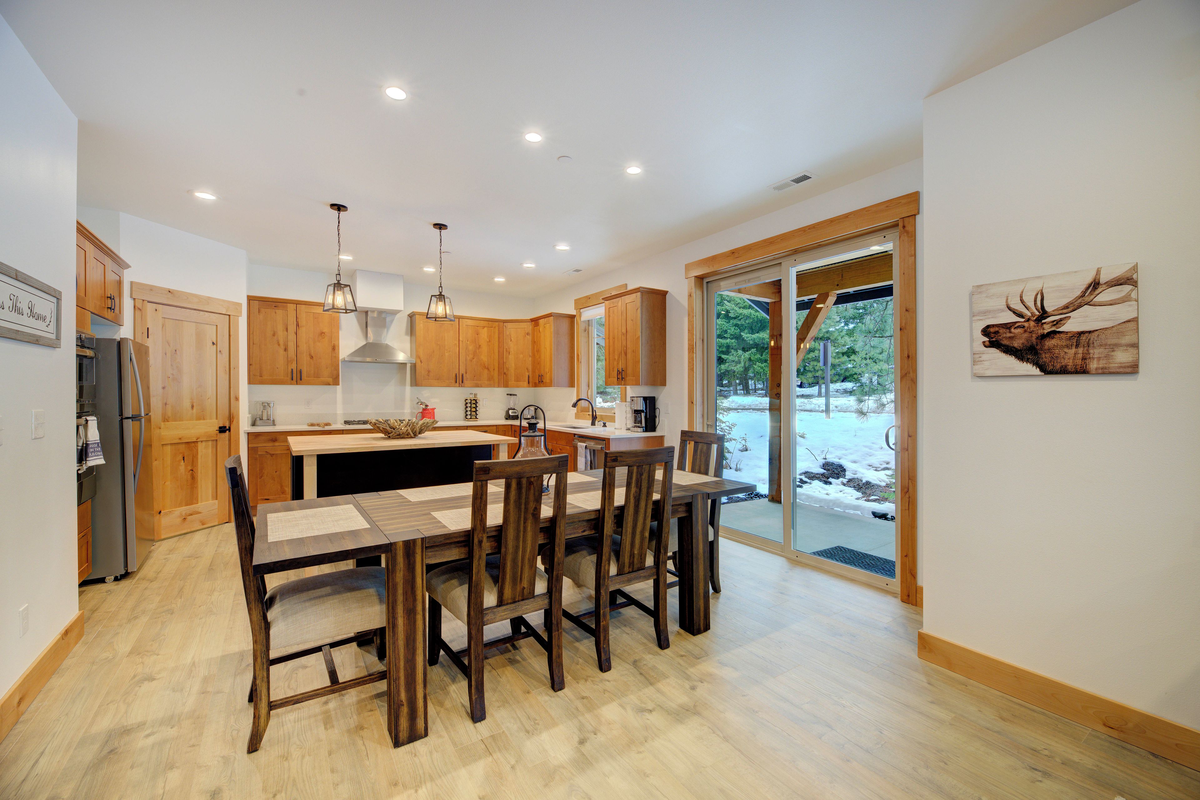 A modern kitchen with wooden cabinets, a central island, and a dining area with wooden chairs.