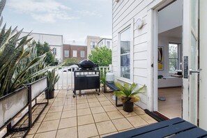 Ein Balkon mit Grill, Blumentöpfen und Blick auf die Nachbarschaft.