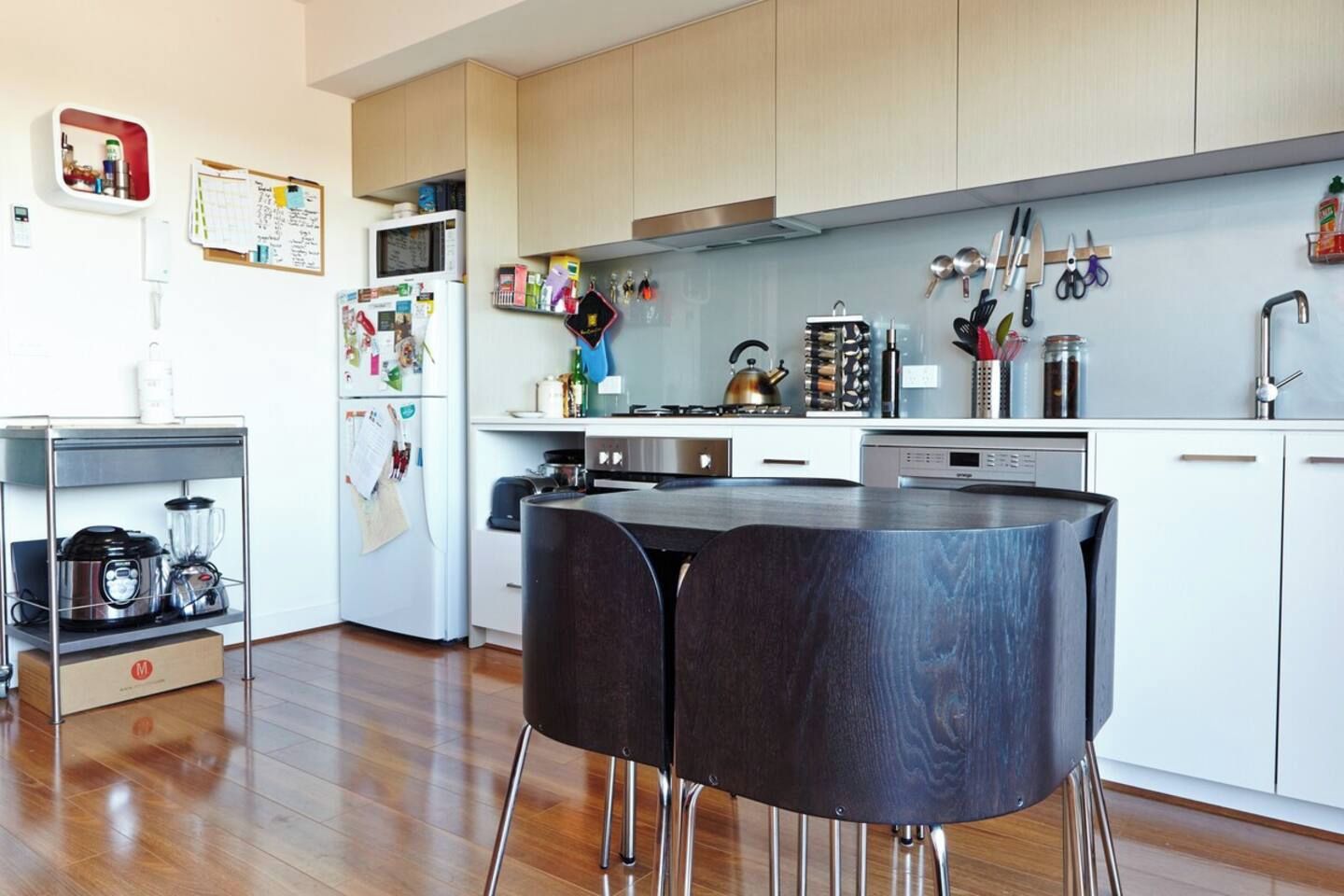 A modern kitchen with wooden cabinets, a microwave, a kettle, and various utensils.