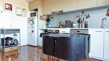 A modern kitchen with wooden cabinets, a microwave, a kettle, and various utensils.