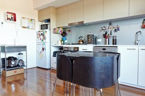 A modern kitchen with wooden cabinets, a microwave, a kettle, and various utensils. - Highview on High St A Balcony Haven in Northcote (Northcote)