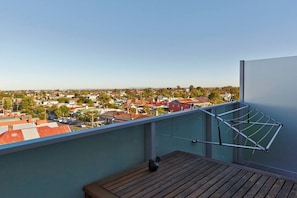 A balcony with a view of a residential area, a drying rack, and a wooden table. - Highview on High St A Balcony Haven in Northcote (Northcote)