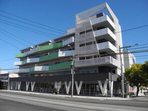 A multi-story building with a modern architectural design, featuring a prominent 'VVV' sign on the ground floor. - Highview on High St A Balcony Haven in Northcote (Northcote)