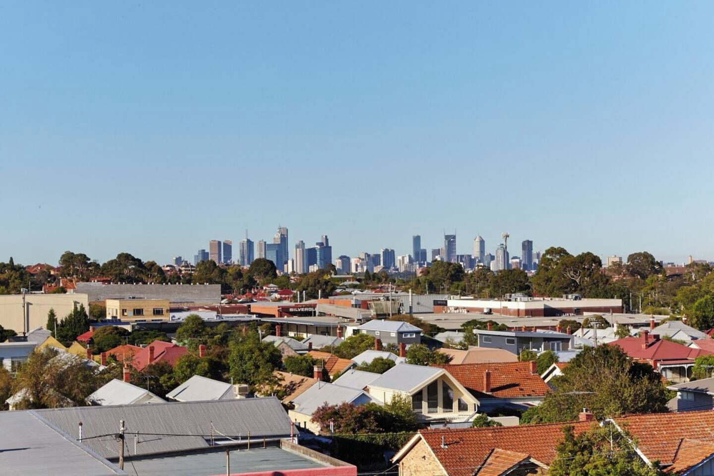 A residential area with a mix of houses and a distant city skyline.