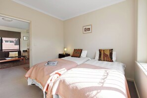 Ein Hotelzimmer mit zwei Betten, einer Sitzecke inklusive Sofa und Tisch, einem kleinen Schreibtisch und einem Fenster.