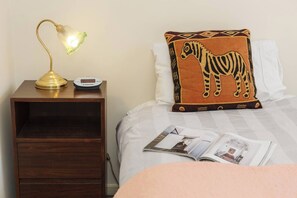 A neatly made bed with a zebra pillow, a bedside lamp, and a magazine on the nightstand. - Northcote Charm Spacious and Quiet Suburban Stay (Northcote)