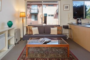 Ein Wohnzimmer mit Sofa, Couchtisch, Heizkörper, Lampe und Blick auf ein Gebäude.