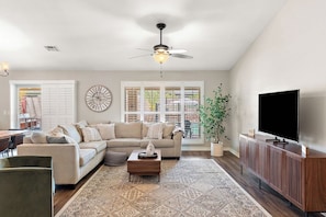 A living room with a sofa, coffee table, TV, and a ceiling fan. - Surprise House 🌵⛳ Fenced Pool & Firepit Near Surprise Stadium (Surprise)
