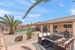 Un patio con piscina, mobiliario exterior y una parrilla.