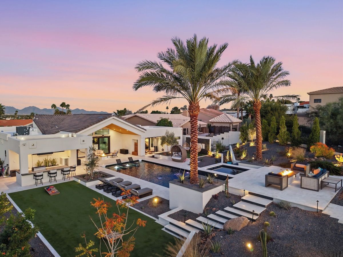 A modern outdoor living area with a pool, seating, and palm trees.