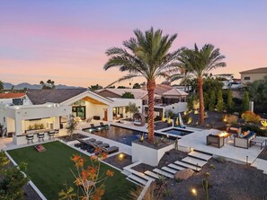 A modern outdoor living area with a pool, seating, and palm trees. - Dos Palms | Luxury | HtdPool, Jacuzzi, Trails! (Phoenix)