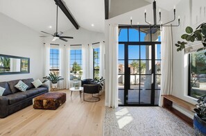 A modern living room with a sofa, coffee table, and a ceiling fan. - Dos Palms | Luxury | HtdPool, Jacuzzi, Trails! (Phoenix)