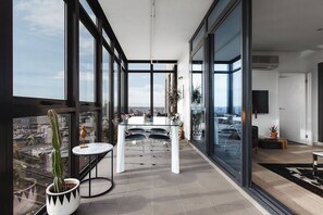 A modern balcony with a city view, a dining table with chairs, and a potted cactus. - Scenic Penthouse Living in the Heart of Melbourne (Southbank)
