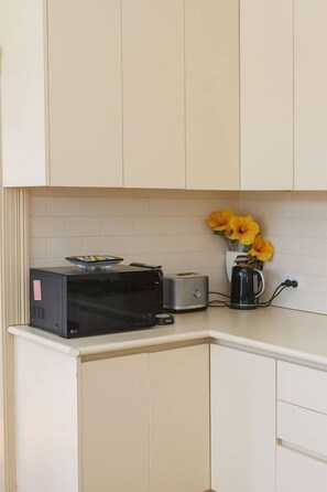 Een keuken met witte kastjes, een magnetron, een broodrooster en een koffiezetapparaat.