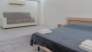 Un dormitorio con cama, sofá, mesita de noche y aire acondicionado.