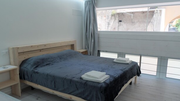 Un dormitorio con una cama de madera, una mesita de noche y una ventana con vistas al exterior.