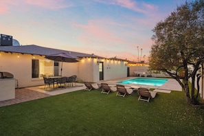 Un jardin avec une piscine, un espace salon extérieur et un coin barbecue.