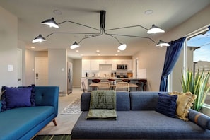 A modern living room with a sofa, a dining area, and a kitchen in the background. - Scottsdale Sheridan Luxe 🌵⛳ Free Heated Pool Near Old Town & Desert Botanical (Scottsdale)